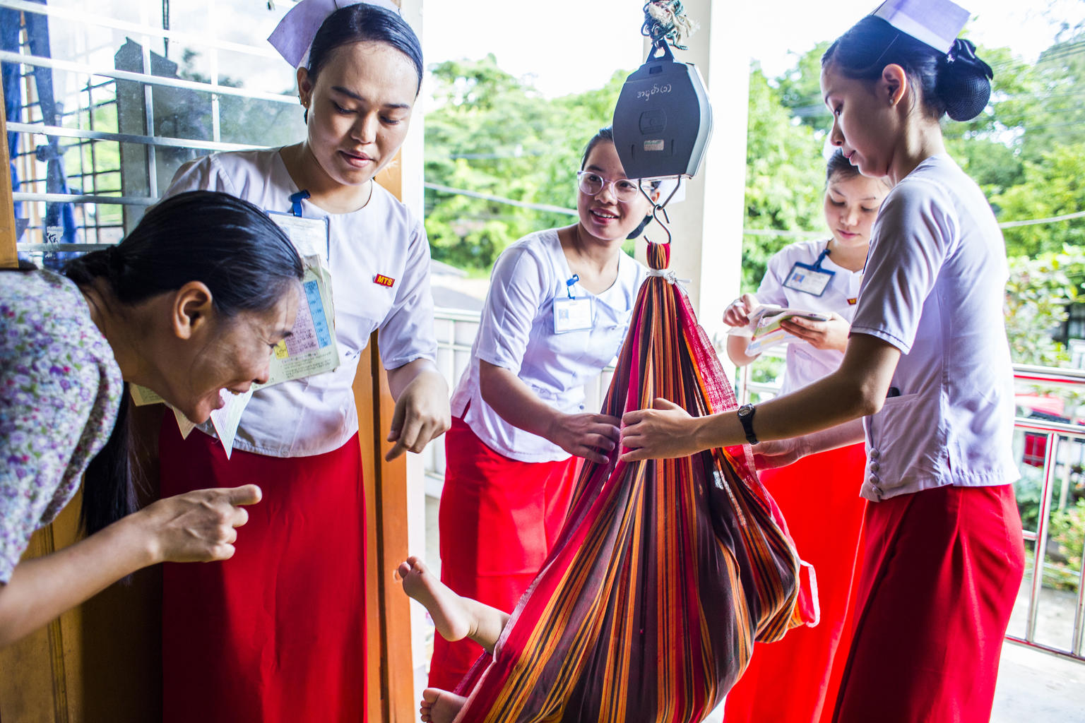 Healthcare workers prepare to weigh a baby on a scale in Kayin State, Myanmar. © UNICEF/UNI218089
